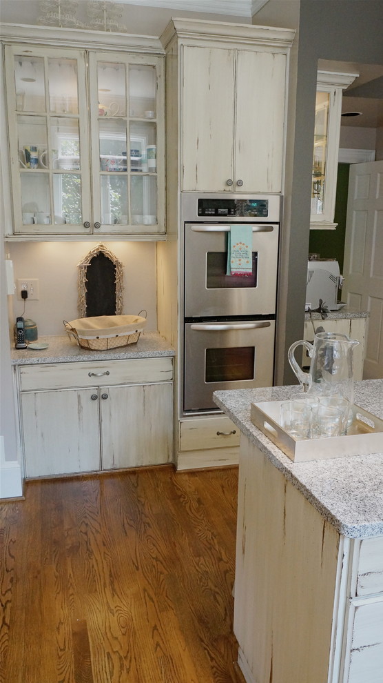 Inspiration for a large rustic u-shaped medium tone wood floor eat-in kitchen remodel in Atlanta with an undermount sink, flat-panel cabinets, distressed cabinets, quartz countertops, white backsplash, ceramic backsplash, stainless steel appliances and beige walls