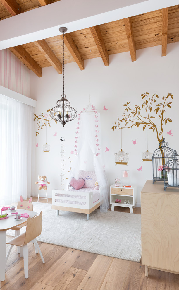 Photo of a mid-sized beach style kids' room for girls in Miami with pink walls, light hardwood floors and beige floor.