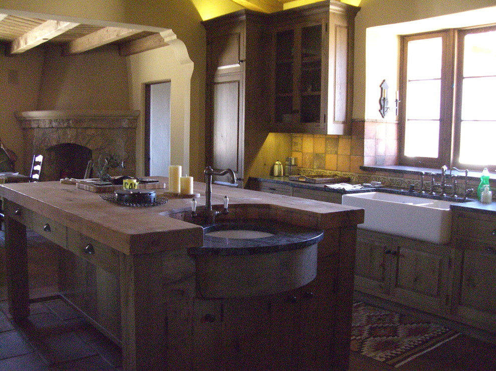 Photo of a large country open plan kitchen in Santa Barbara with a farmhouse sink, raised-panel cabinets, medium wood cabinets, soapstone benchtops, multi-coloured splashback, terra-cotta splashback, panelled appliances, terra-cotta floors and with island.