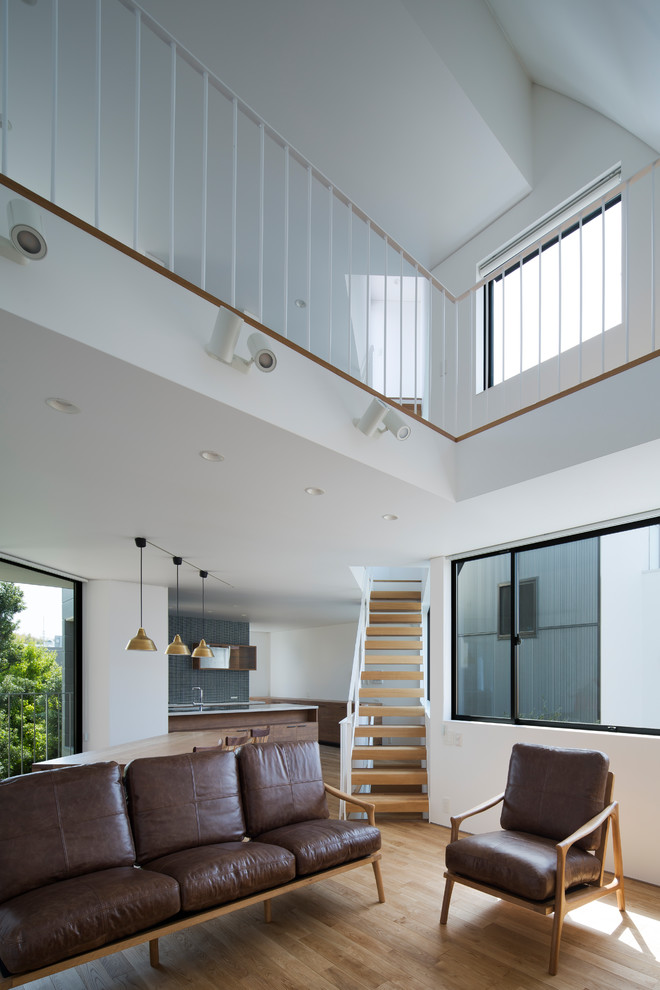 Scandinavian open concept living room in Osaka with white walls, light hardwood floors and brown floor.