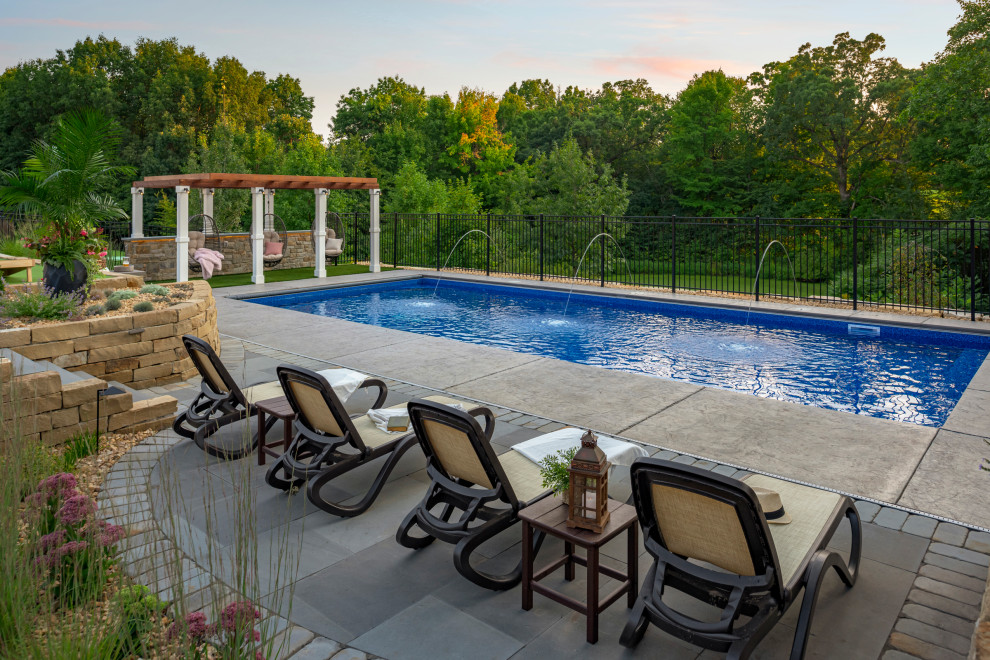 This is an example of a large traditional backyard pool in Minneapolis with natural stone pavers.