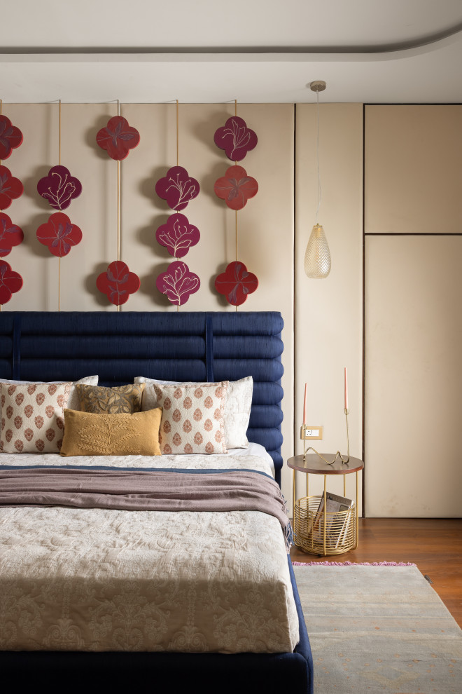 Inspiration for a contemporary bedroom in Bengaluru With Beige Walls and Medium Hardwood Floors.