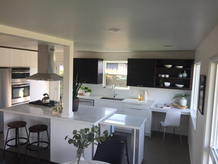 Inspiration for a medium sized modern l-shaped kitchen/diner in Los Angeles with flat-panel cabinets, white splashback, stainless steel appliances, an island and white worktops.
