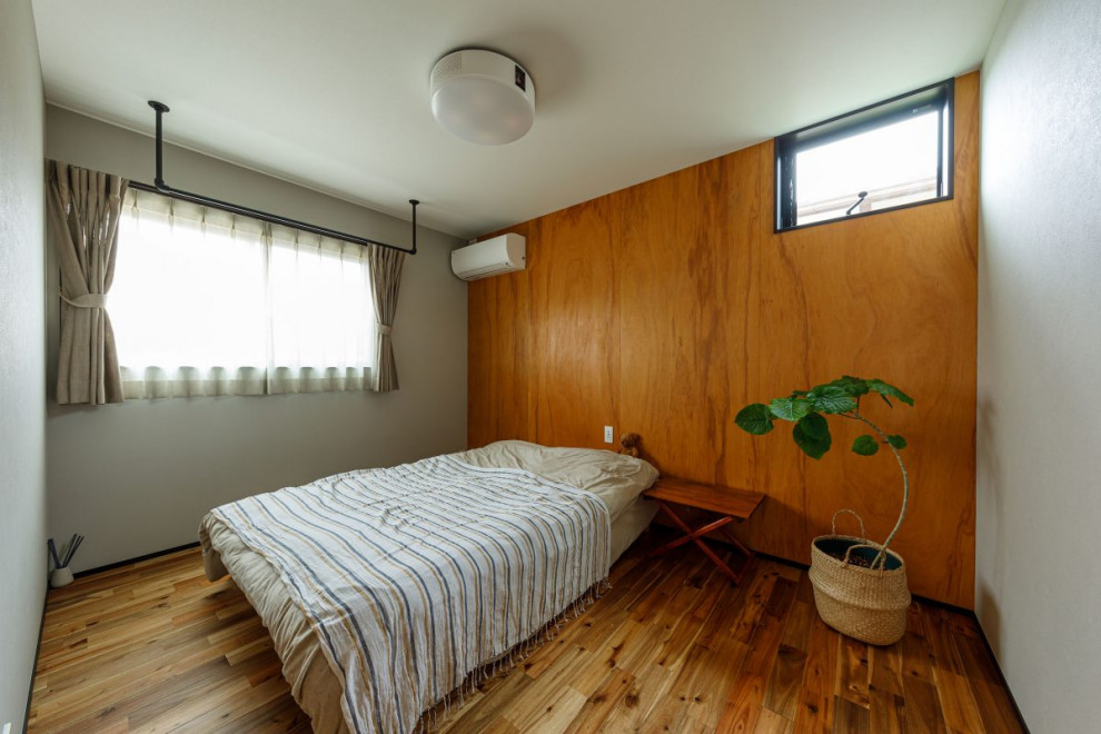 This is an example of a mid-sized industrial master bedroom in Tokyo with white walls, medium hardwood floors, no fireplace, brown floor, wallpaper and wallpaper.
