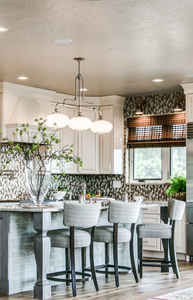 This is an example of a large transitional l-shaped separate kitchen in Denver with raised-panel cabinets, beige cabinets, multi-coloured splashback, mosaic tile splashback, with island, an undermount sink, granite benchtops, stainless steel appliances, light hardwood floors and brown floor.