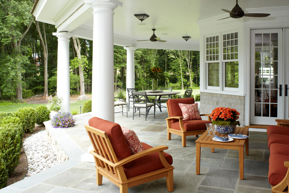 Design ideas for a large traditional backyard verandah in New York with a roof extension and natural stone pavers.