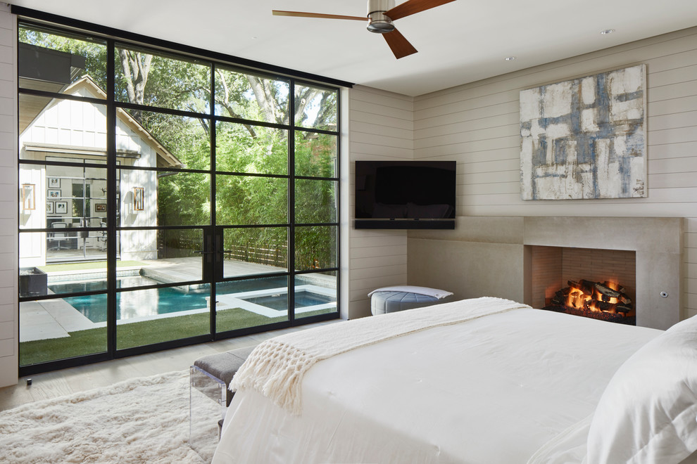 Inspiration for a country master bedroom in Austin with a standard fireplace, a concrete fireplace surround and beige walls.