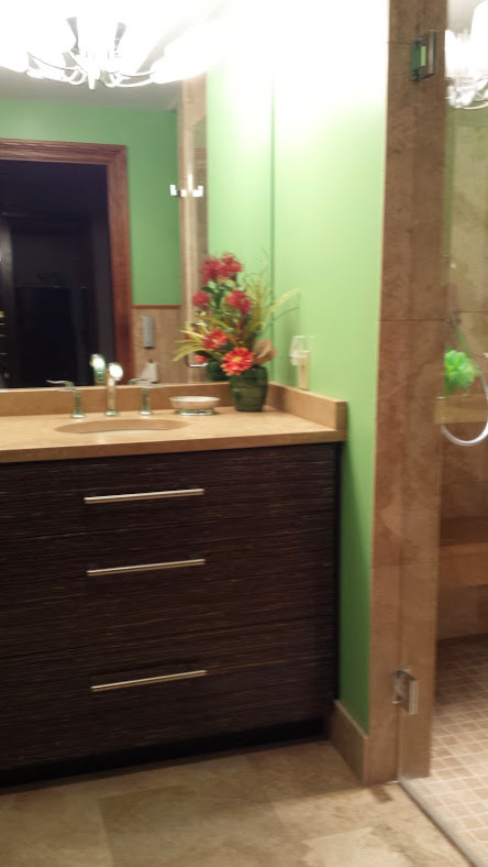 Inspiration for a small eclectic 3/4 beige tile and stone tile travertine floor home design remodel with a wall-mount toilet, green walls, an undermount sink, brown cabinets and limestone countertops