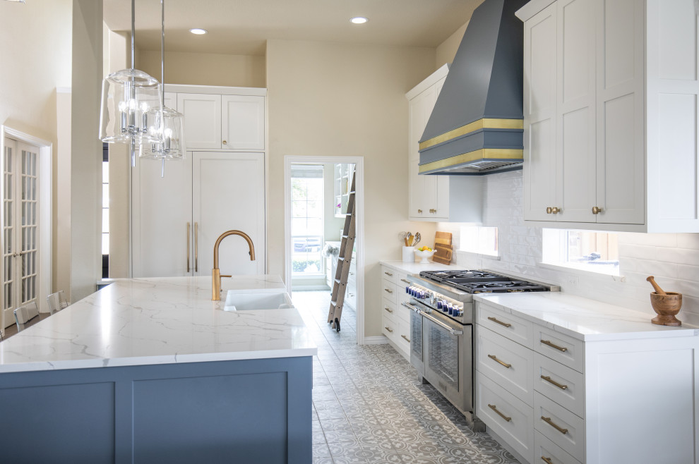 Inspiration for a large transitional l-shaped eat-in kitchen in Dallas with a farmhouse sink, shaker cabinets, white cabinets, quartz benchtops, white splashback, subway tile splashback, stainless steel appliances, porcelain floors, with island, multi-coloured floor and white benchtop.
