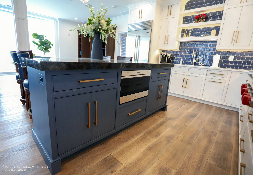 Open concept kitchen - large transitional u-shaped medium tone wood floor open concept kitchen idea with a single-bowl sink, flat-panel cabinets, white cabinets, quartz countertops, blue backsplash, glass tile backsplash, stainless steel appliances, an island and white countertops