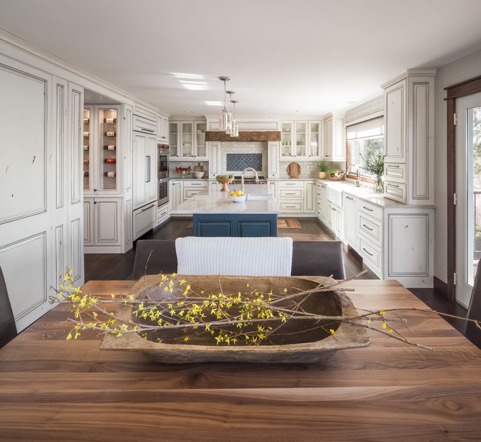 Large transitional u-shaped dark wood floor and brown floor eat-in kitchen photo in Denver with a farmhouse sink, raised-panel cabinets, distressed cabinets, quartzite countertops, multicolored backsplash, ceramic backsplash, paneled appliances, an island and white countertops