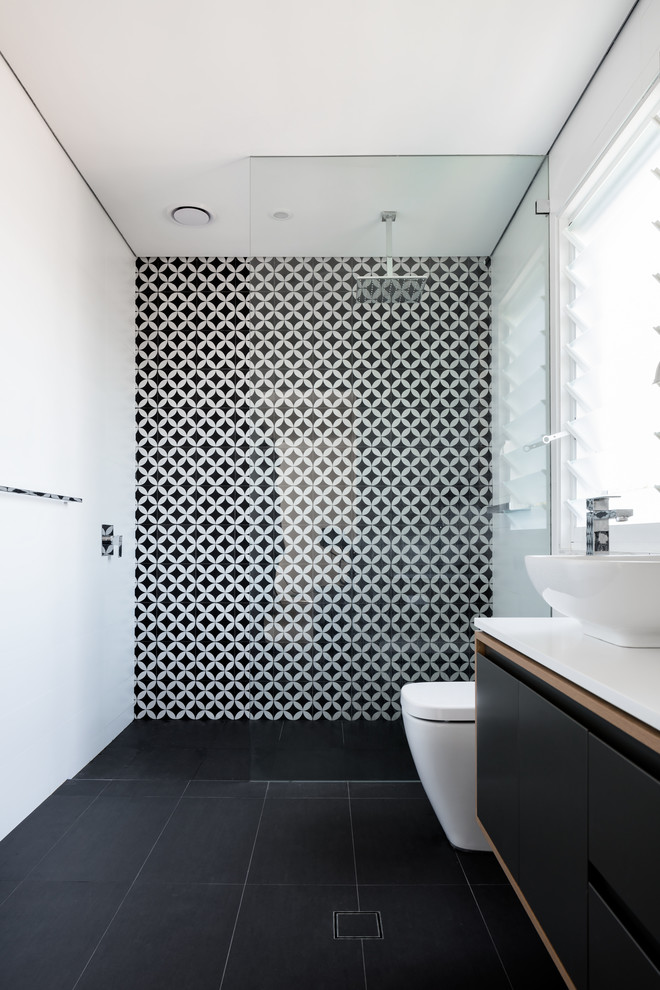 This is an example of a contemporary bathroom in Sydney with a vessel sink, flat-panel cabinets, black cabinets, a curbless shower, a one-piece toilet, ceramic tile, multi-coloured walls and black and white tile.