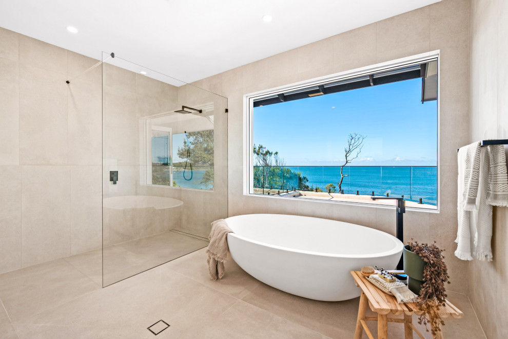 Design ideas for a large beach style master bathroom in Central Coast with a freestanding tub, beige tile, an open shower, a curbless shower and beige floor.