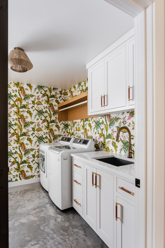 Idee per una lavanderia tradizionale con lavello sottopiano, ante in stile shaker, ante bianche, pareti multicolore, pavimento in cemento, lavatrice e asciugatrice affiancate, pavimento grigio, top bianco e carta da parati