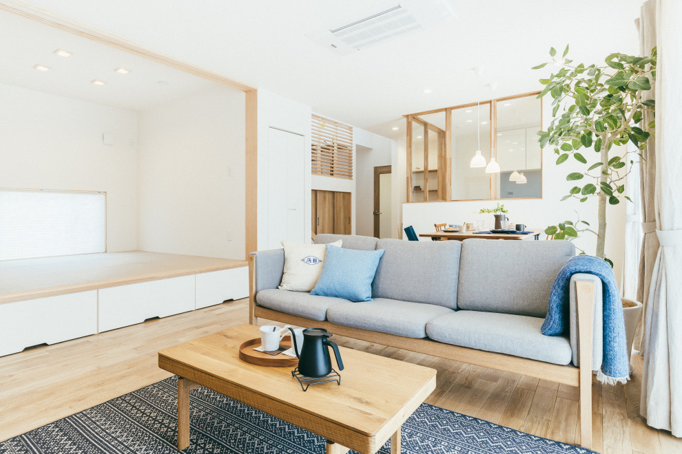 This is an example of a mid-sized scandinavian open concept living room in Other with white walls, medium hardwood floors, no fireplace and a wall-mounted tv.