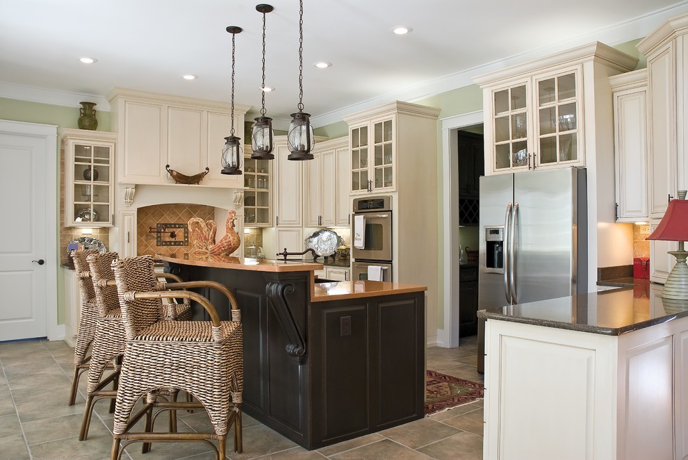 This is an example of a mid-sized traditional l-shaped kitchen in Denver with beige cabinets, granite benchtops, beige splashback, stone tile splashback, stainless steel appliances, slate floors, with island, glass-front cabinets and beige floor.