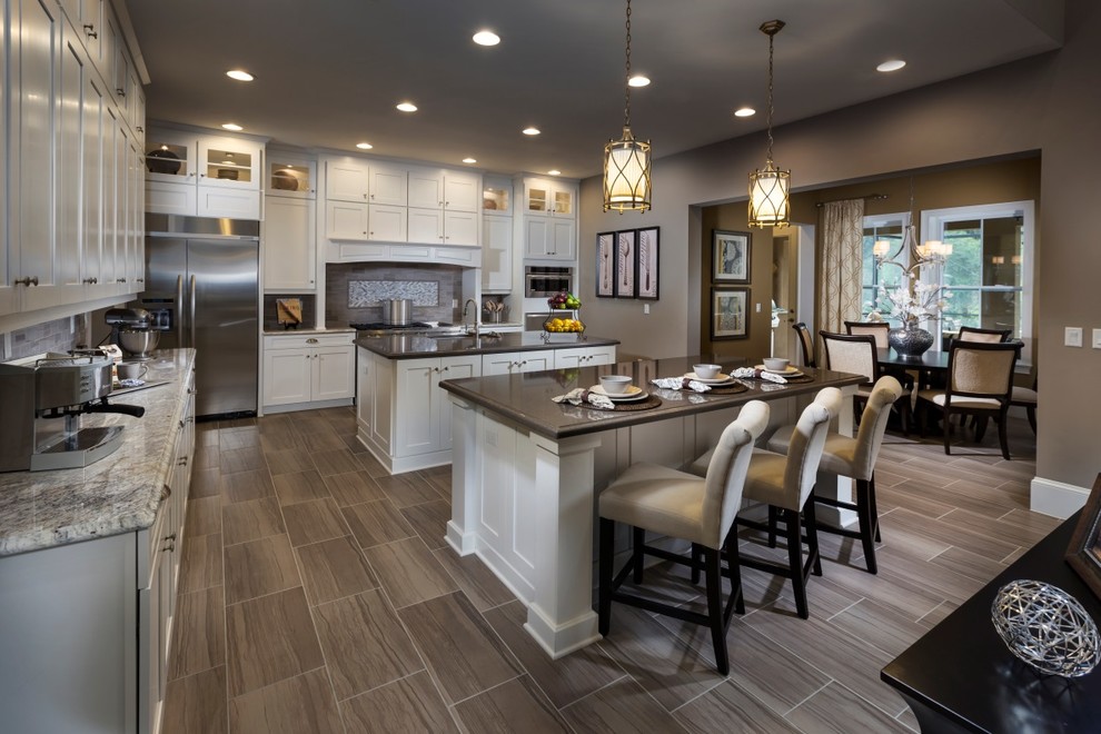 Transitional l-shaped eat-in kitchen in Tampa with shaker cabinets, white cabinets, granite benchtops, stainless steel appliances, ceramic floors and multiple islands.