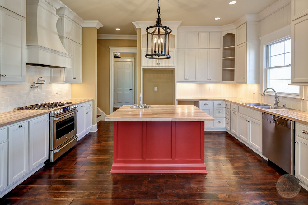 Photo of a large traditional u-shaped kitchen in Louisville with a double-bowl sink, shaker cabinets, white cabinets, wood benchtops, white splashback, subway tile splashback, dark hardwood floors, with island and brown floor.