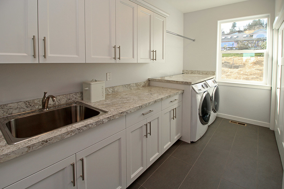 Large transitional single-wall utility room in Seattle with a single-bowl sink, shaker cabinets, white cabinets, laminate benchtops, grey walls, porcelain floors and a side-by-side washer and dryer.