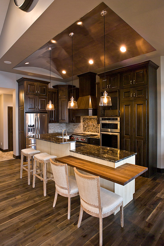 Eat-in kitchen - small transitional l-shaped medium tone wood floor and brown floor eat-in kitchen idea with an undermount sink, raised-panel cabinets, dark wood cabinets, granite countertops, multicolored backsplash, subway tile backsplash, stainless steel appliances and an island