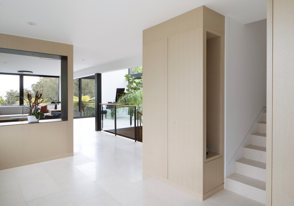 Idee per un ingresso minimalista di medie dimensioni con pareti bianche, pavimento in pietra calcarea, una porta singola, una porta in legno bruno e pavimento bianco