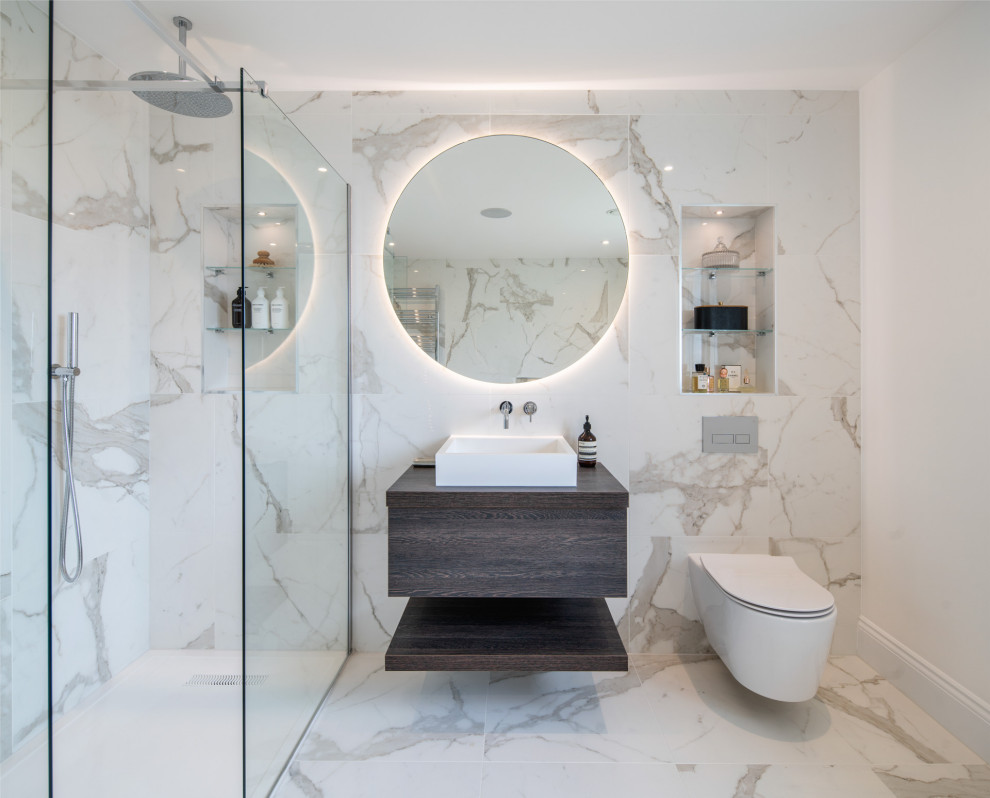 This is an example of a contemporary bathroom in London with flat-panel cabinets, dark wood cabinets, a built-in shower, white tiles, white walls, a vessel sink, white floors, a hinged door, brown worktops, a single sink and a floating vanity unit.