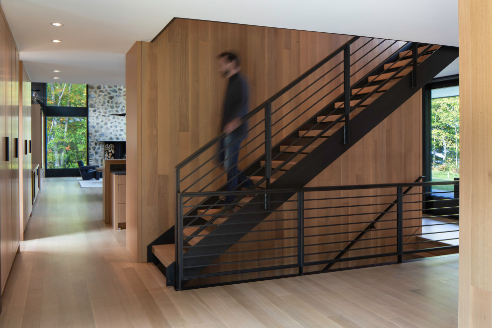 Imagen de escalera suspendida actual de tamaño medio sin contrahuella con escalones de madera, barandilla de metal y madera