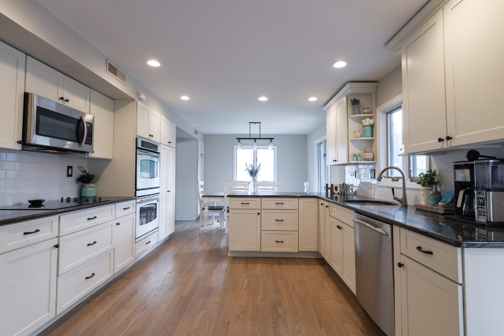 Inspiration for a mid-sized transitional galley medium tone wood floor and brown floor kitchen remodel in Philadelphia with an undermount sink, beaded inset cabinets, white cabinets, white backsplash, subway tile backsplash, stainless steel appliances and no island