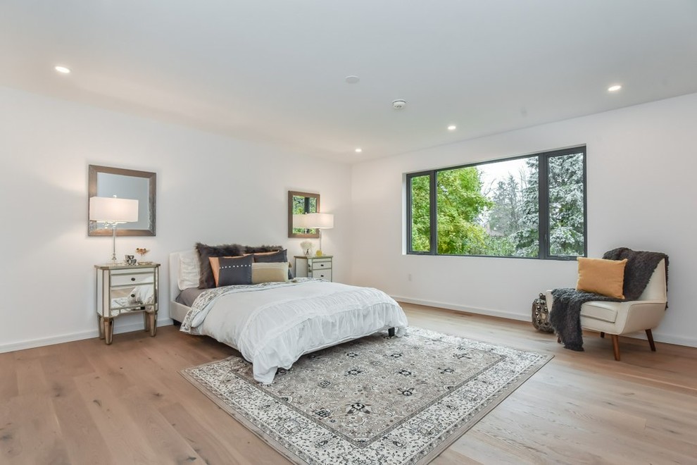 Imagen de dormitorio principal moderno grande sin chimenea con paredes blancas, suelo de madera clara y suelo beige