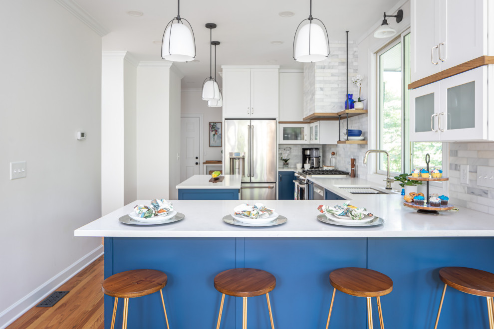 Inspiration for a mid-sized transitional l-shaped medium tone wood floor and brown floor eat-in kitchen remodel in Raleigh with an undermount sink, shaker cabinets, blue cabinets, quartzite countertops, white backsplash, marble backsplash, stainless steel appliances, an island and white countertops
