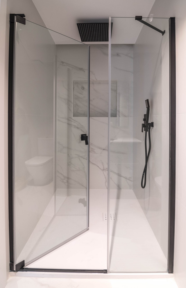 Foto på ett mellanstort minimalistiskt vit en-suite badrum, med släta luckor, vita skåp, en dusch i en alkov, ett urinoar, svart och vit kakel, keramikplattor, vita väggar, ett nedsänkt handfat, vitt golv och dusch med gångjärnsdörr