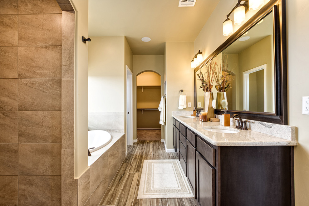 Photo of a transitional master bathroom in Other with shaker cabinets, brown cabinets, an alcove tub, beige walls, painted wood floors, an undermount sink, multi-coloured floor and beige benchtops.