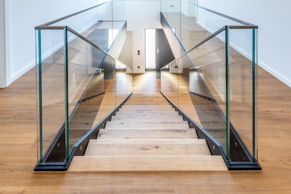 Cette image montre un escalier sans contremarche design avec des marches en bois et un garde-corps en verre.