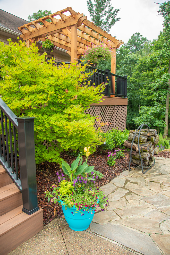 This is an example of a mid-sized transitional drought-tolerant and full sun backyard stone landscaping for summer.