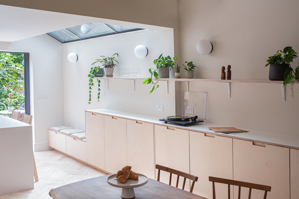 Immagine di una cucina scandinava di medie dimensioni con ante lisce, ante in legno chiaro, top in superficie solida, paraspruzzi bianco, elettrodomestici neri, parquet chiaro e top bianco