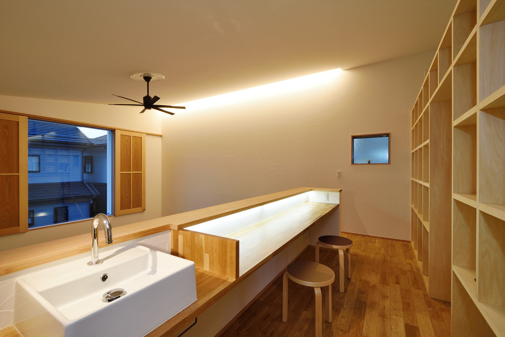 Diseño de despacho blanco nórdico grande sin chimenea con paredes blancas, suelo de madera en tonos medios, escritorio empotrado, suelo marrón, papel pintado y papel pintado