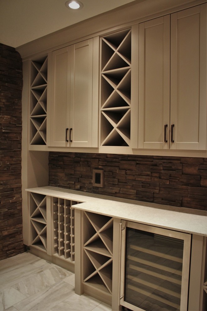 This is an example of a mid-sized contemporary single-wall wet bar in Calgary with recessed-panel cabinets, grey cabinets, stone tile splashback, quartz benchtops, brown splashback, porcelain floors, grey floor and white benchtop.