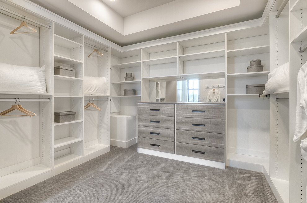 This is an example of a transitional walk-in wardrobe in Seattle with flat-panel cabinets, white cabinets and carpet.