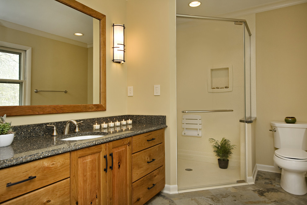 This is an example of a mid-sized transitional master bathroom in Raleigh with raised-panel cabinets, medium wood cabinets, a corner shower, a two-piece toilet, white tile, beige walls, porcelain floors, an undermount sink, engineered quartz benchtops, multi-coloured floor, a hinged shower door and blue benchtops.