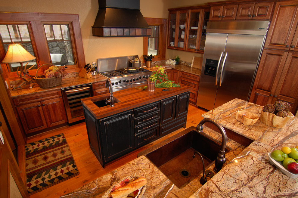 Example of a mountain style u-shaped light wood floor eat-in kitchen design in Charlotte with a farmhouse sink, raised-panel cabinets, medium tone wood cabinets, marble countertops, brown backsplash, stainless steel appliances, beige walls and an island