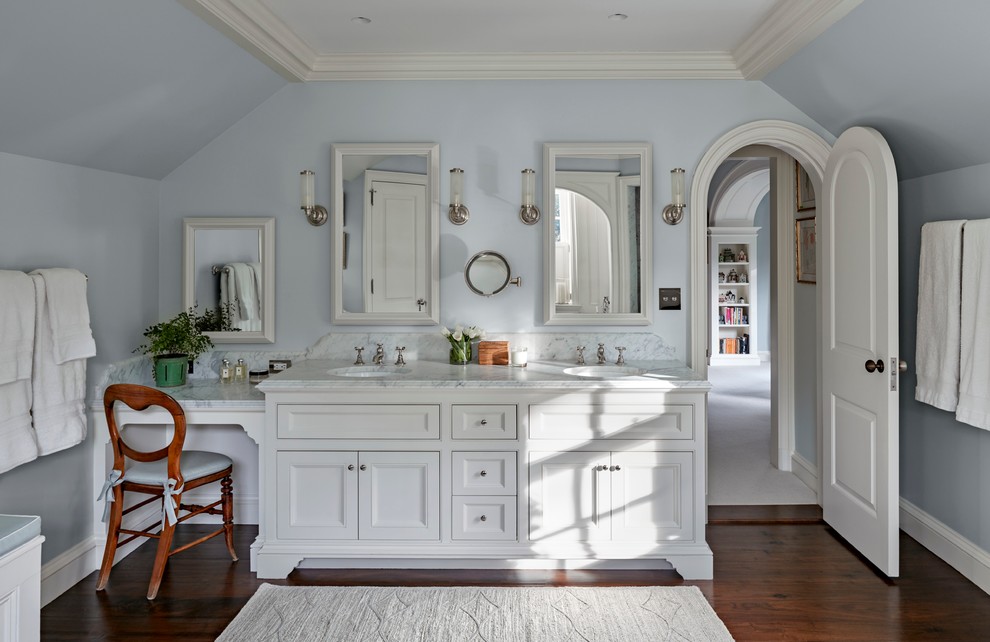 This is an example of a large traditional master bathroom in New York with recessed-panel cabinets, white cabinets, an undermount tub, an alcove shower, white tile, stone tile, blue walls, dark hardwood floors, an undermount sink and marble benchtops.