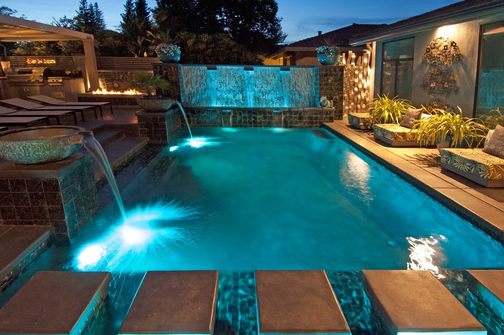 Large transitional backyard concrete paver and rectangular lap water slide photo in Orange County