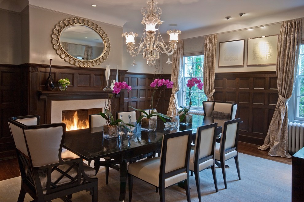 Photo of a large transitional separate dining room in New York with beige walls, dark hardwood floors, a standard fireplace and a stone fireplace surround.
