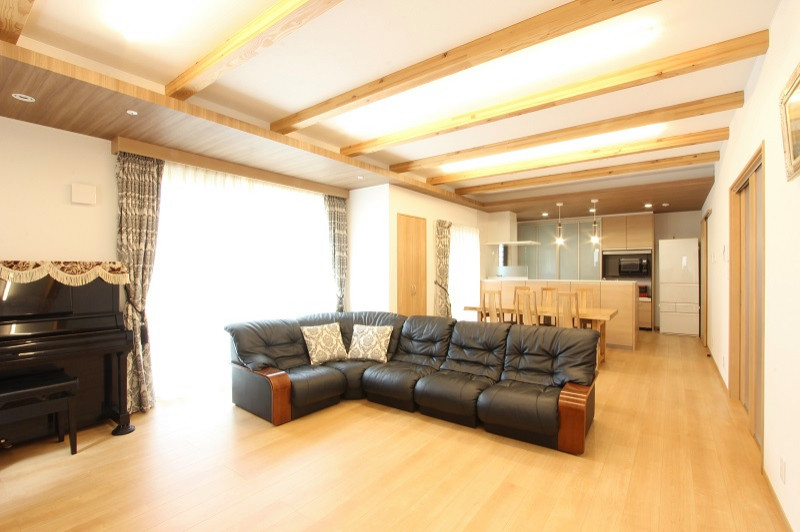 福岡にある広い和モダンなおしゃれなLDK (白い壁、合板フローリング、暖炉なし、据え置き型テレビ、ベージュの床、表し梁、壁紙、黒いソファ、ベージュの天井) の写真