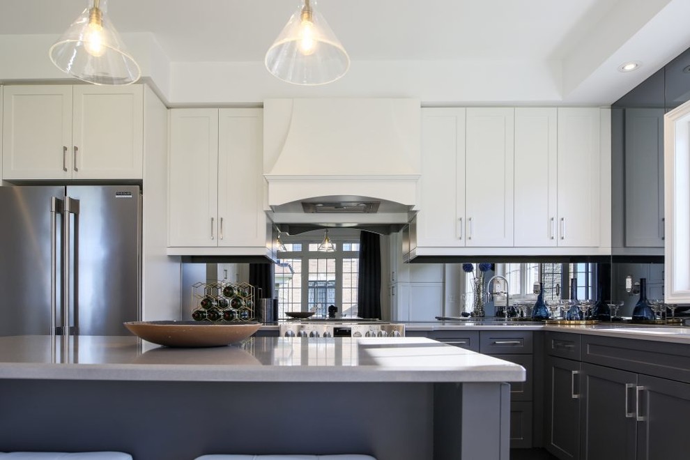 Design ideas for a mid-sized transitional l-shaped open plan kitchen in Toronto with an undermount sink, shaker cabinets, white cabinets, quartz benchtops, mirror splashback, stainless steel appliances, dark hardwood floors, with island and grey benchtop.