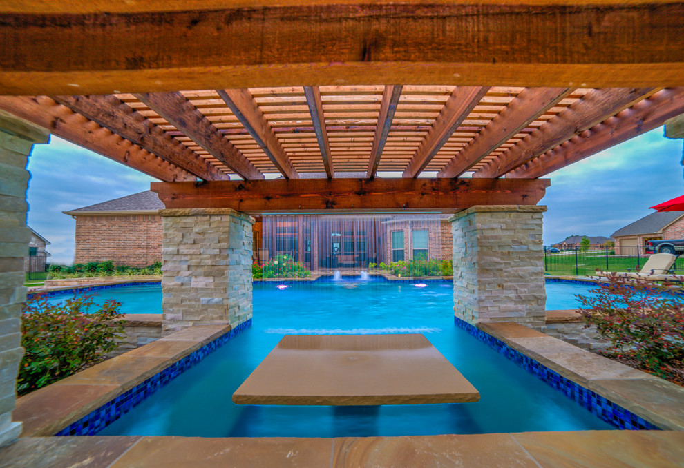 This is an example of an expansive contemporary backyard custom-shaped pool in Dallas with a water feature and natural stone pavers.