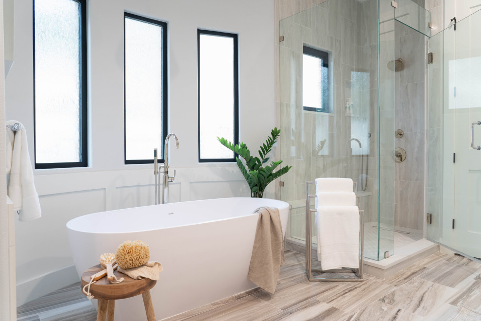 Klassisches Badezimmer mit freistehender Badewanne, grauen Fliesen, weißer Wandfarbe, grauem Boden und vertäfelten Wänden in Austin