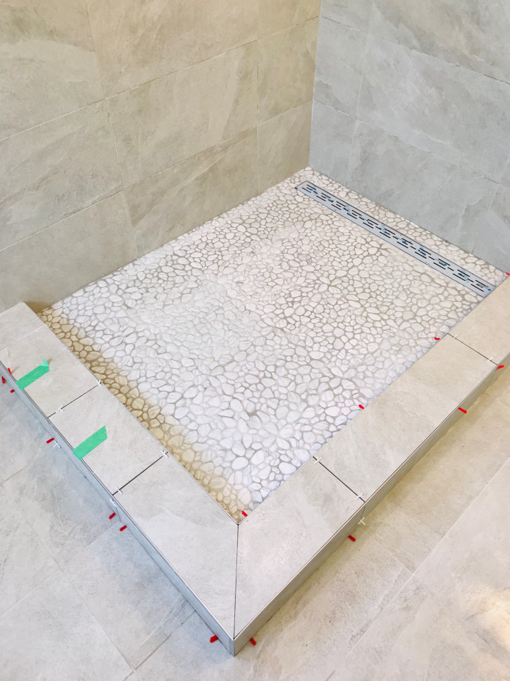 Immagine di una stanza da bagno padronale minimalista di medie dimensioni con doccia ad angolo, piastrelle beige, piastrelle in gres porcellanato, pareti beige, pavimento con piastrelle di ciottoli, pavimento bianco, porta doccia a battente e nicchia