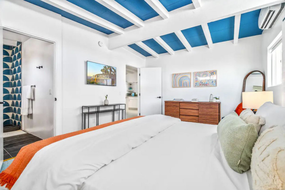 Foto di una camera matrimoniale moderna con pareti bianche, pavimento in laminato, pavimento blu, travi a vista e pareti in mattoni