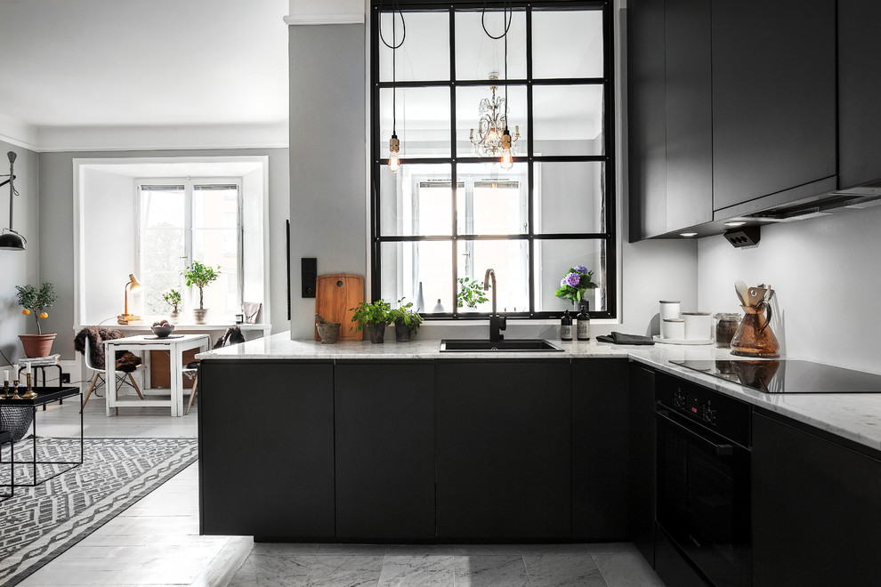 Large scandinavian l-shaped eat-in kitchen in Stockholm with a drop-in sink, flat-panel cabinets, black cabinets, marble benchtops, black appliances and no island.